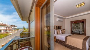 A balcony with a glass door leading to a bedroom with a bed, a small table, and a chair.