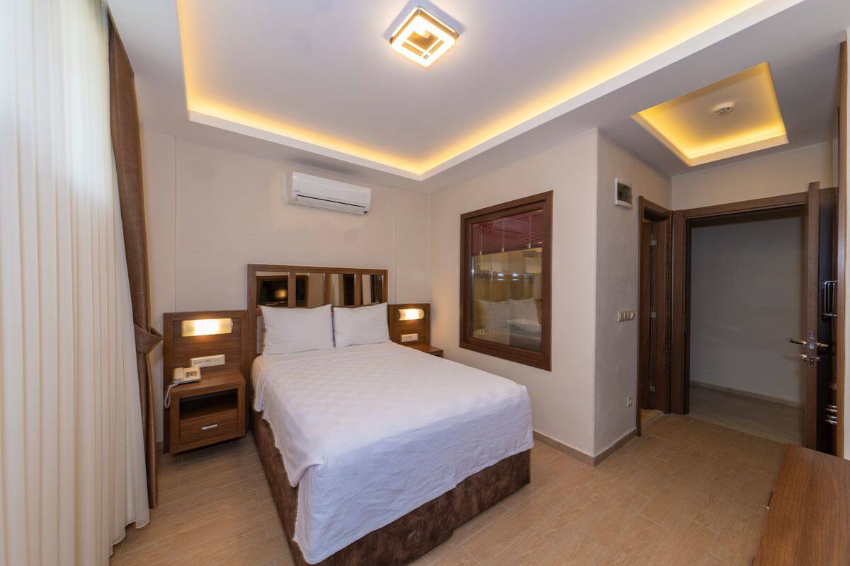 Une chambre d’hôtel avec un grand lit, des tables de chevet avec des lampes, un miroir et un luminaire au plafond.