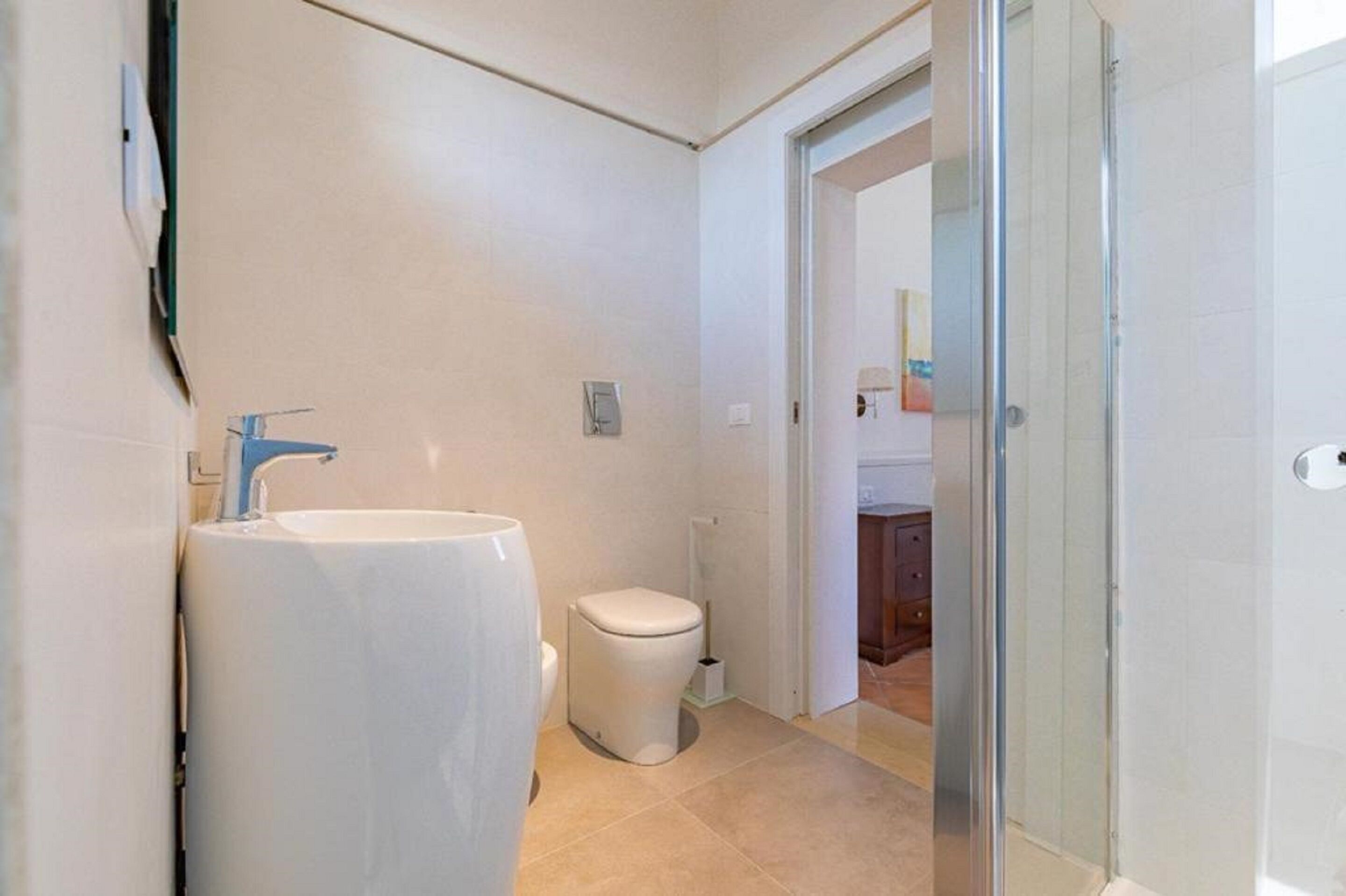 A bathroom with a large sink, toilet, and a glass shower enclosure.