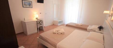 A hotel room with a bed, bedside table, desk, chair, and a window with curtains.