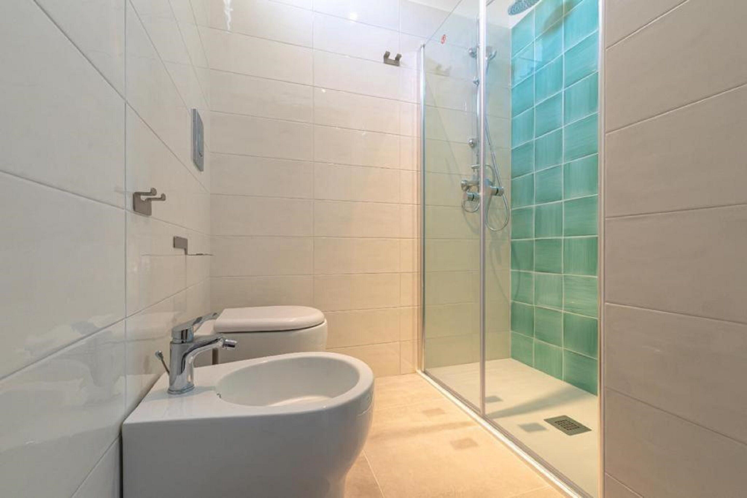 A modern bathroom with a glass-enclosed shower, a white sink, and a toilet.