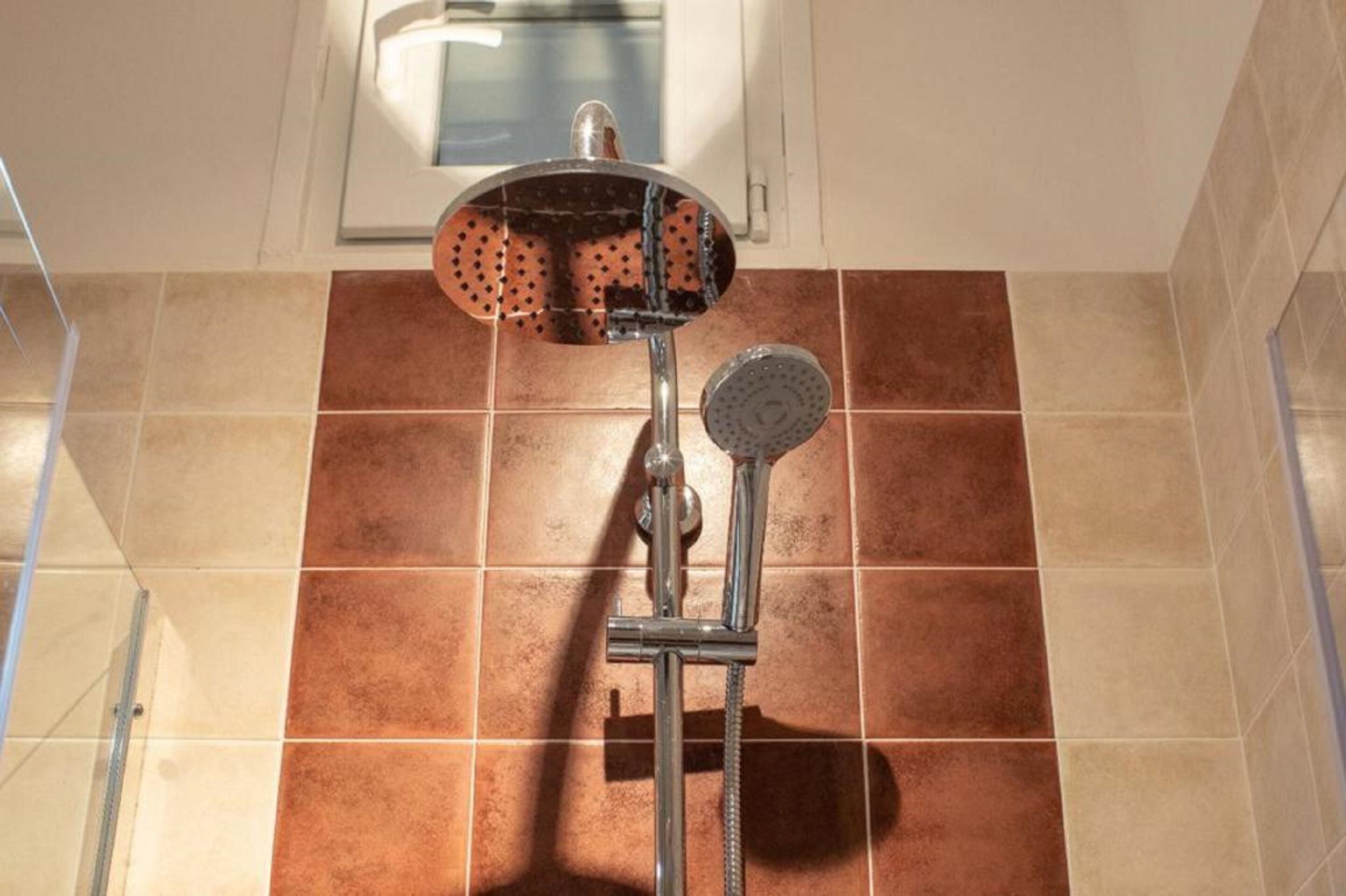 A shower with a handheld showerhead and a wall-mounted faucet.