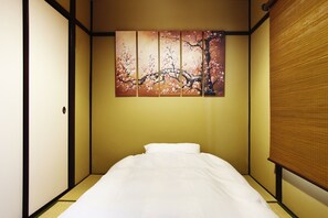 A traditional Japanese-style room with tatami flooring, a low bed, and a sliding door. - Gion Kyuraku (Kyoto)