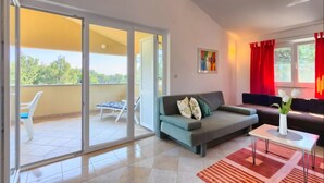 A living room with a sofa, a coffee table, and a sliding glass door leading to an outdoor balcony.