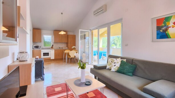 A modern living room with a grey sofa, a coffee table, and a dining area with a table and chairs.