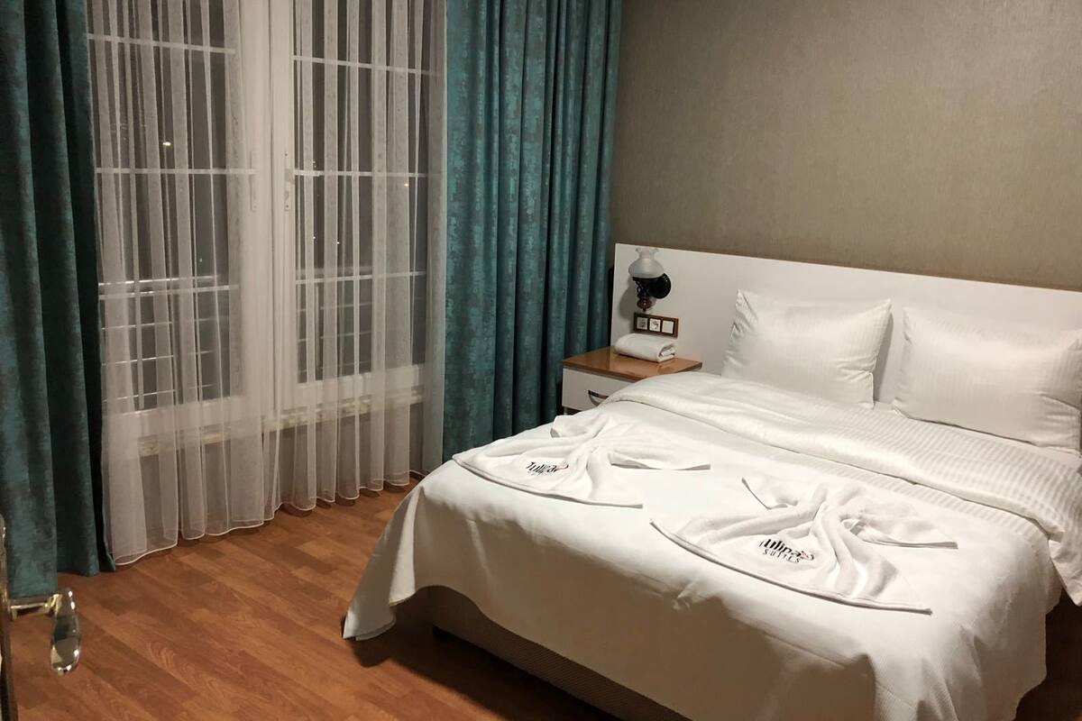 Ein Hotelzimmer mit einem großen Bett, einem Nachttisch mit Lampe und transparenten Vorhängen.