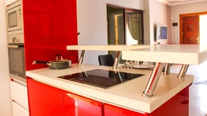 Una cocina moderna con una pared de acento roja, estufa integrada y encimera blanca.