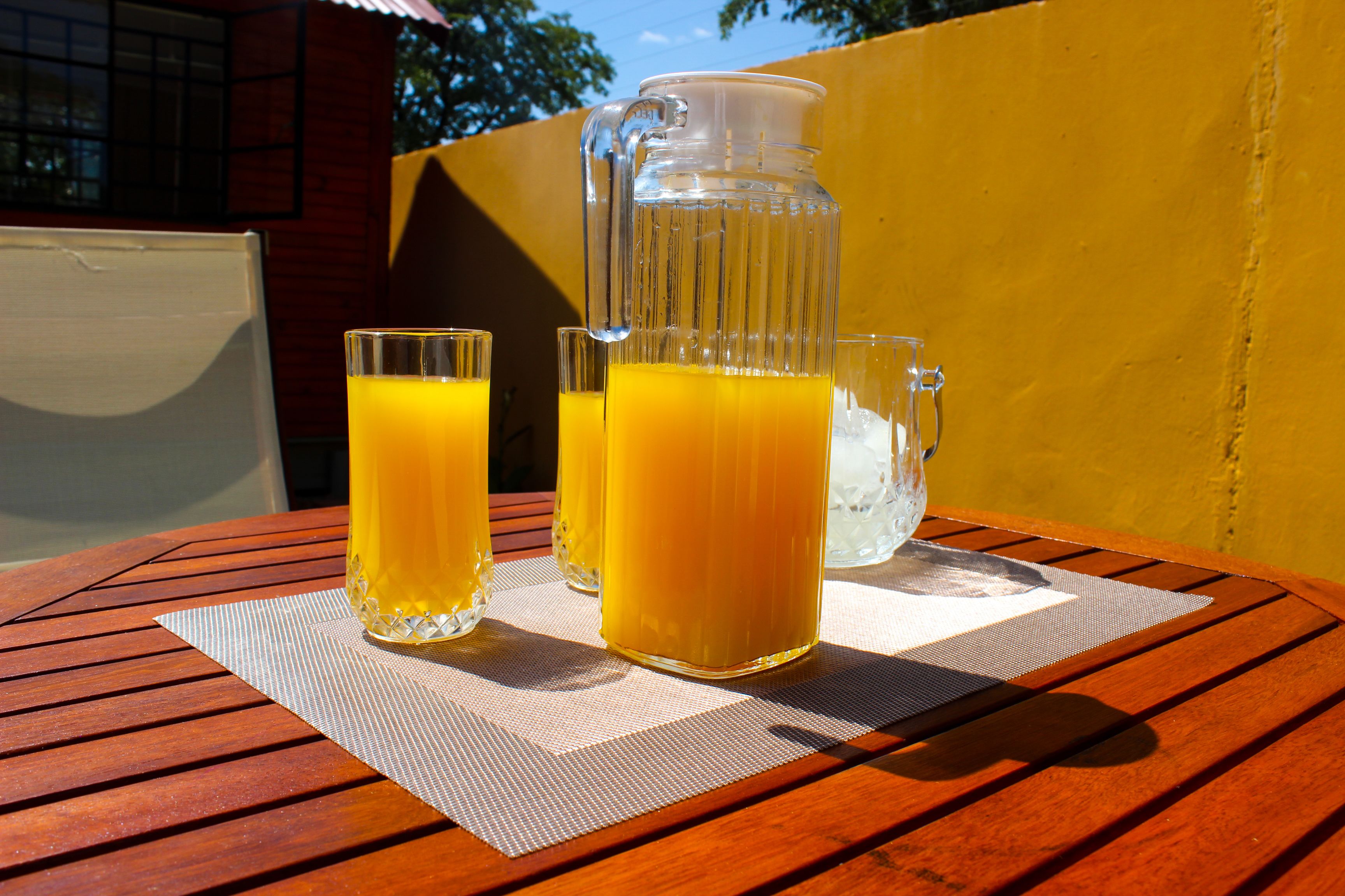 A wooden table with a pitcher and two glasses of orange juice.