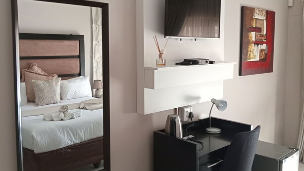 Una habitación de hotel moderna con cama, escritorio, televisor y basurero.