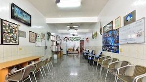 A waiting area with chairs, a reception desk, a television, and framed pictures on the walls. - YoYo MaAn B&B (Liuqiu)