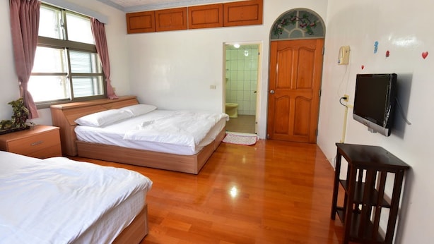 A bedroom with a double bed, a bedside table, a TV mounted on the wall, and a wooden door. - YoYo MaAn B&B (Liuqiu)