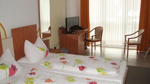 Una habitación de hotel con una cama, un escritorio, una silla y un televisor.
