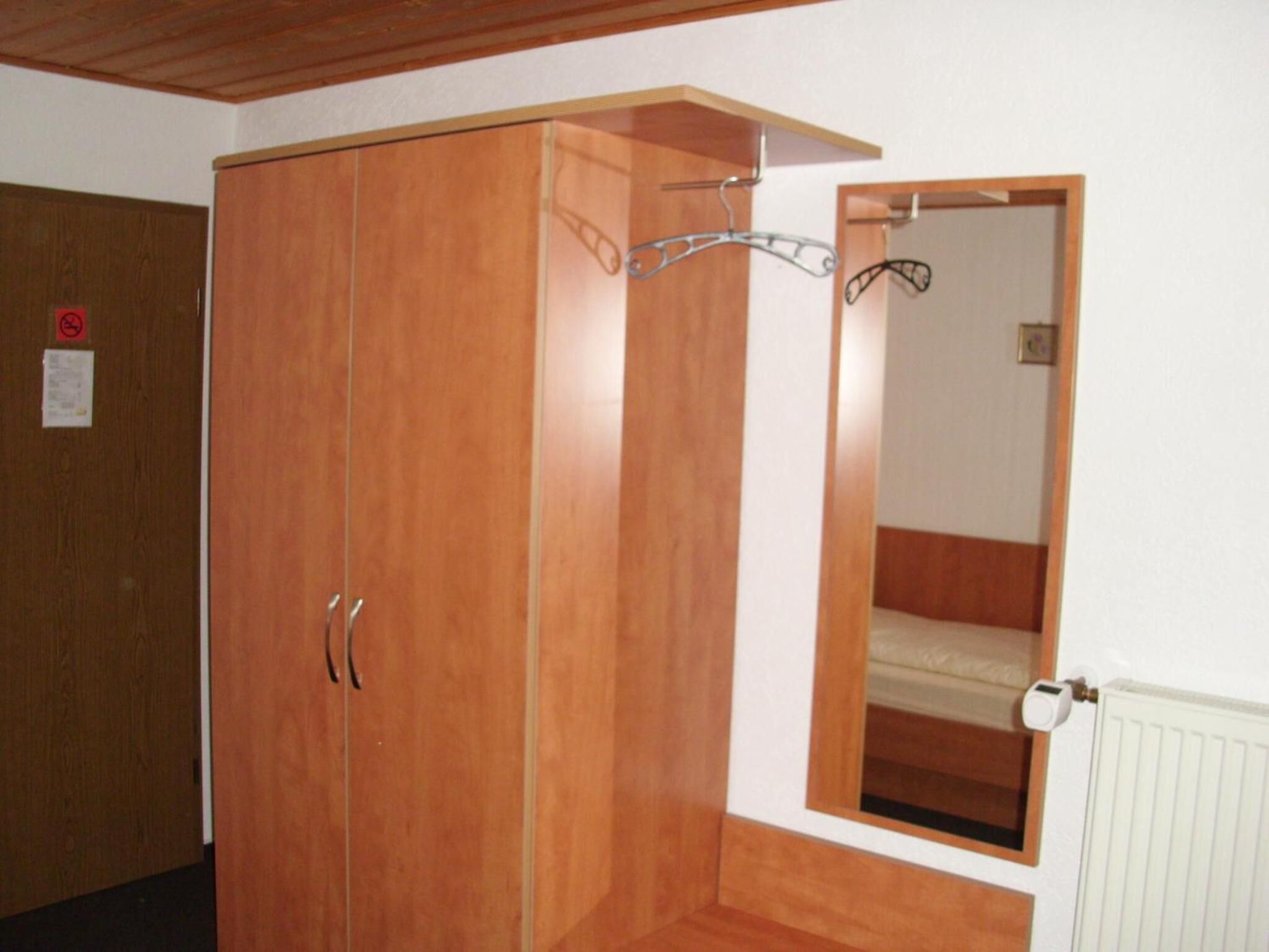 Un dormitorio con un armario de madera, un espejo y un radiador.