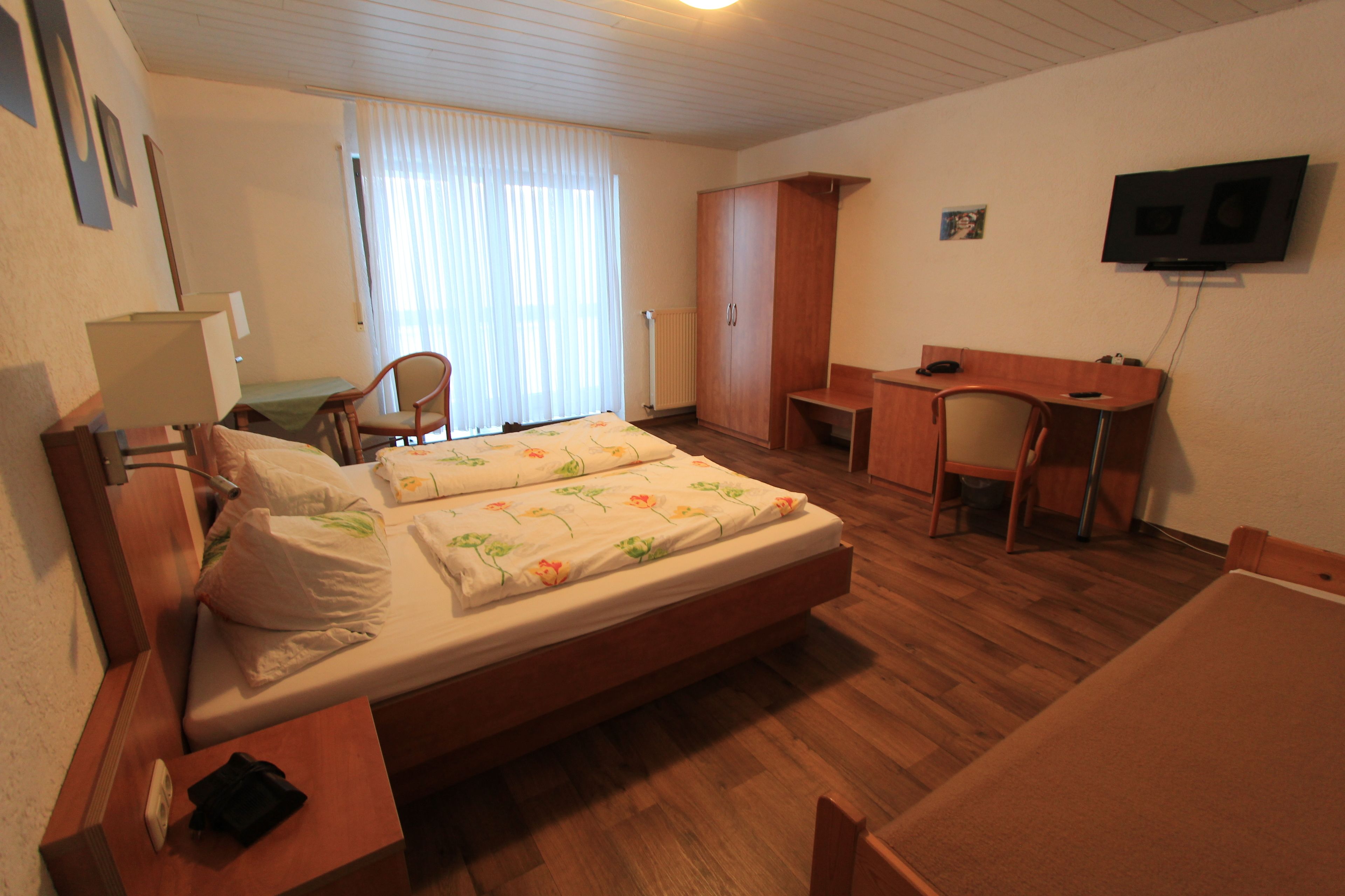 Una camera d'albergo con un letto, una scrivania, una sedia, un armadio e una televisione.