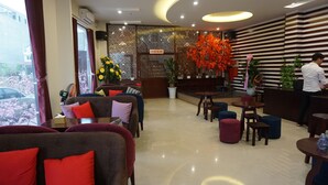Un hall de hotel con sofás, mesas y una recepción.