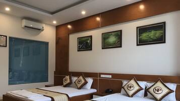 Habitación de hotel con dos camas, un ventanal con persianas y tres cuadros en la pared.