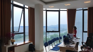 Un salón de conferencias con una gran mesa, sillas y una computadora portátil.