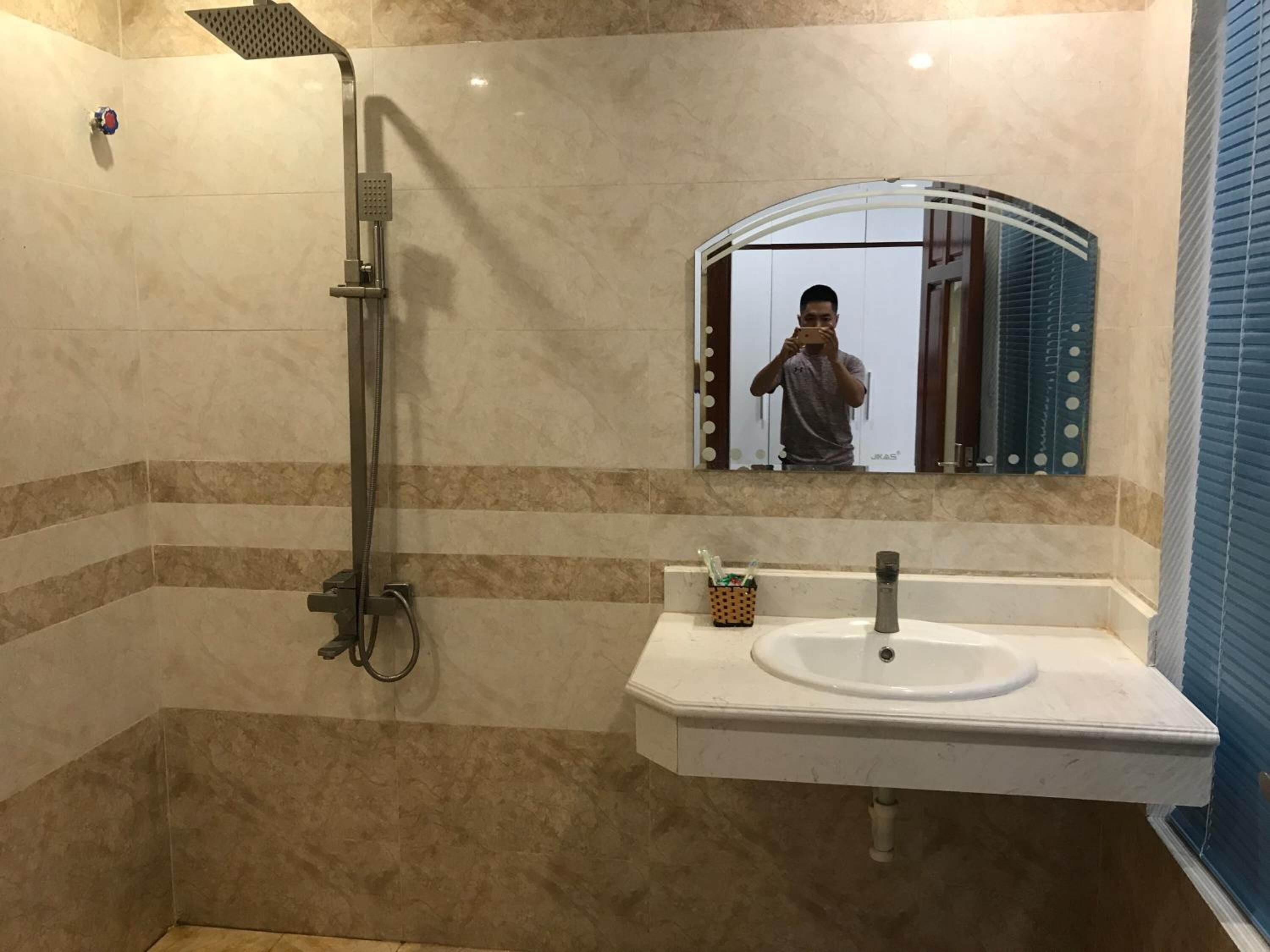 A bathroom with a shower, sink, and mirror.