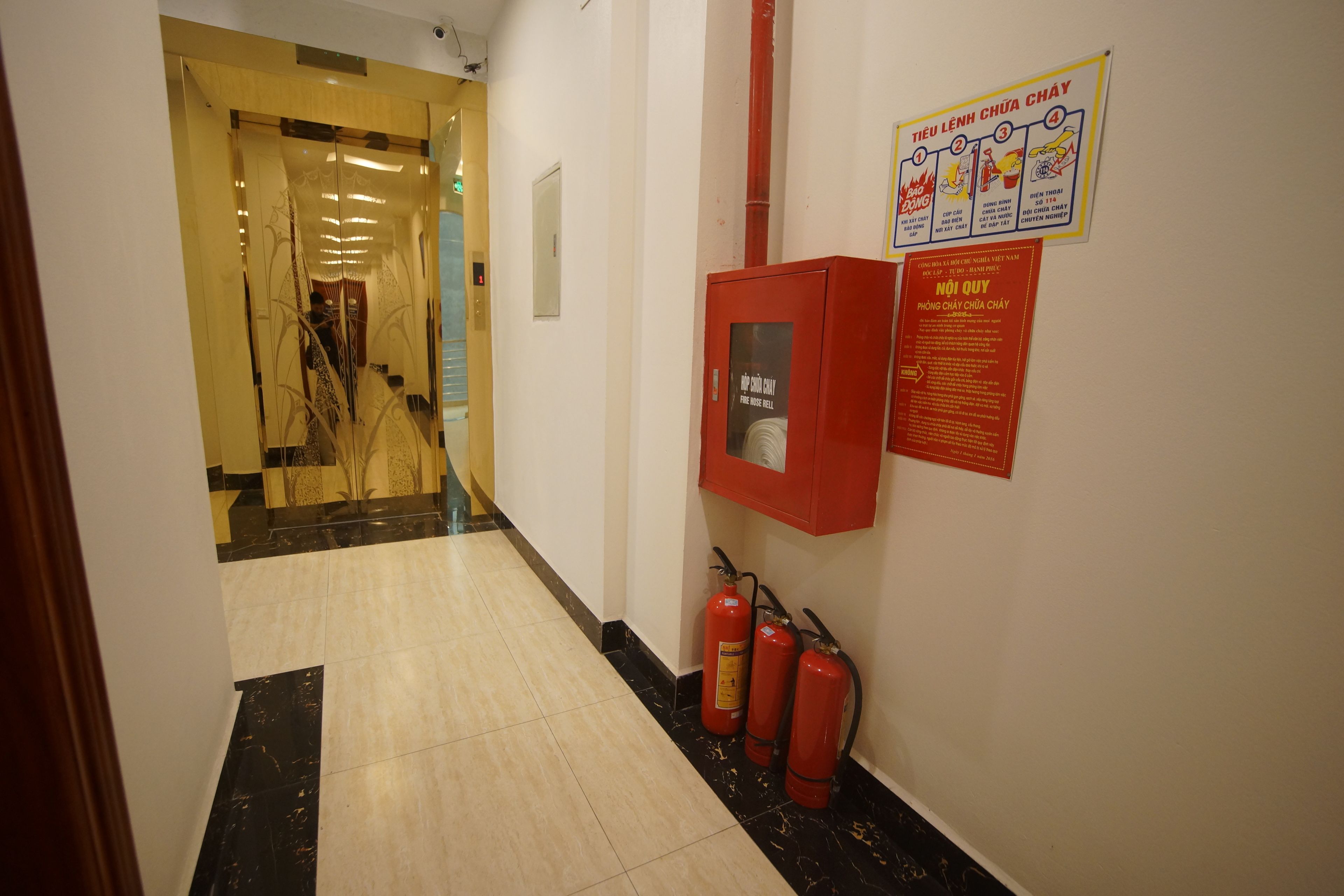 Un couloir avec un extincteur et une affiche sur la sécurité incendie accrochée au mur.