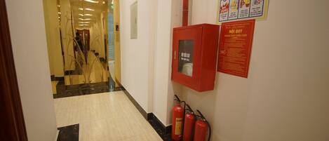 A hallway with a fire extinguisher and a fire safety poster on the wall.