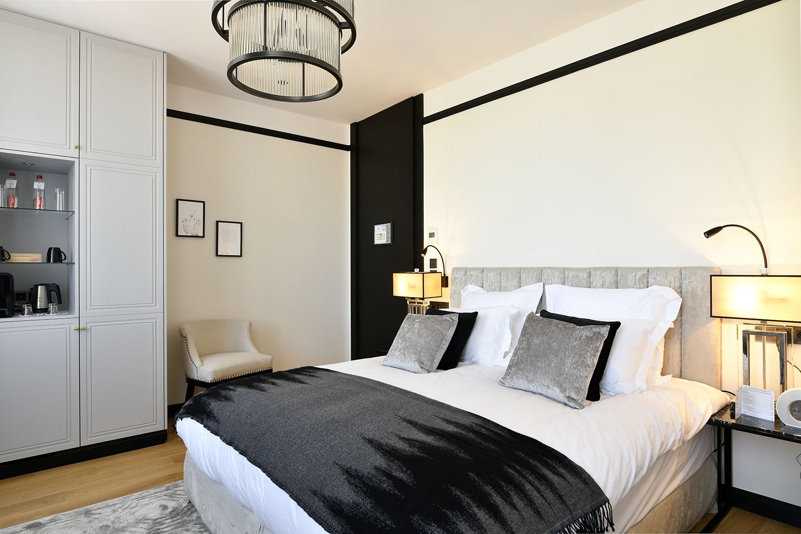 Een moderne hotelkamer met een groot bed, een kledingkast, een zithoek en een kroonluchter.