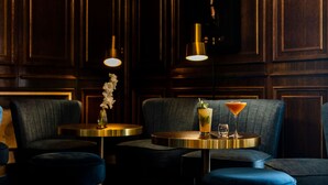 A dark wooden paneled room with a sofa, ottoman, and a small table with drinks. - Hôtel Restaurant Le Touring (Saint-Raphael)