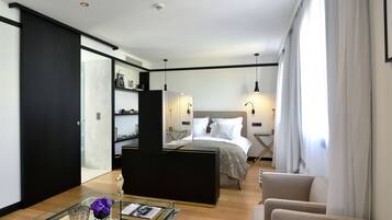 A modern hotel room with a bed, a glass coffee table, a sofa, and a desk.