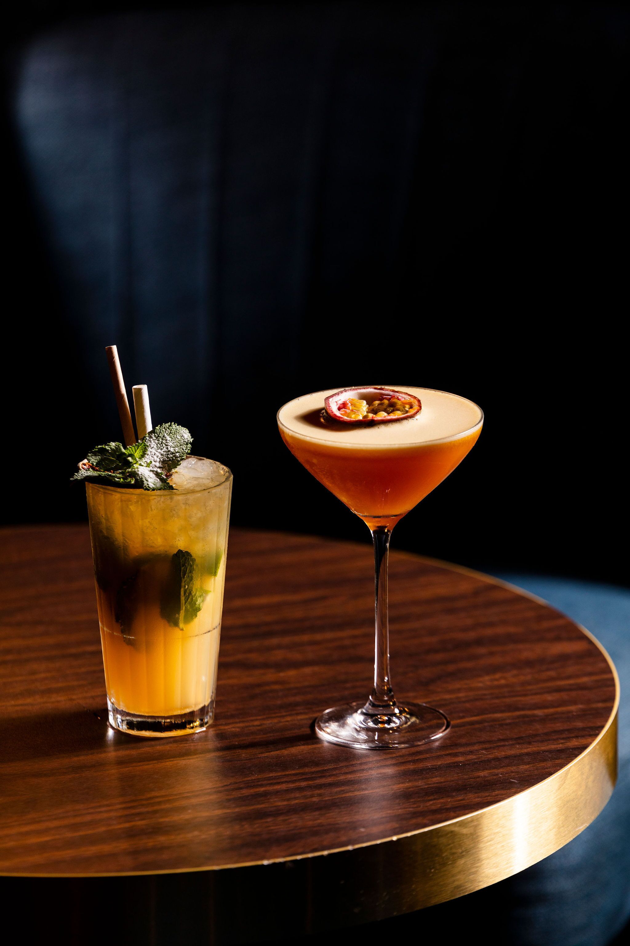 Two drinks on a round table with a dark background.
