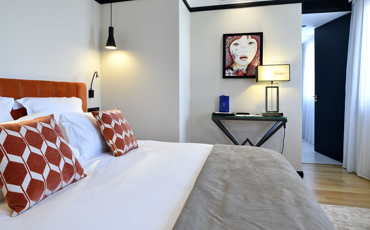 Una habitación de hotel con una cama, una mesita de noche, una lámpara y un cuadro en la pared.