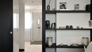 A modern hotel room with a bed, a coffee machine, a bookshelf, and a shower area. - Hôtel Restaurant Le Touring (Saint-Raphael)