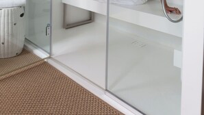 A modern bathroom with a glass-enclosed shower area, a white sink, and a wicker basket. - Hôtel Restaurant Le Touring (Saint-Raphael)