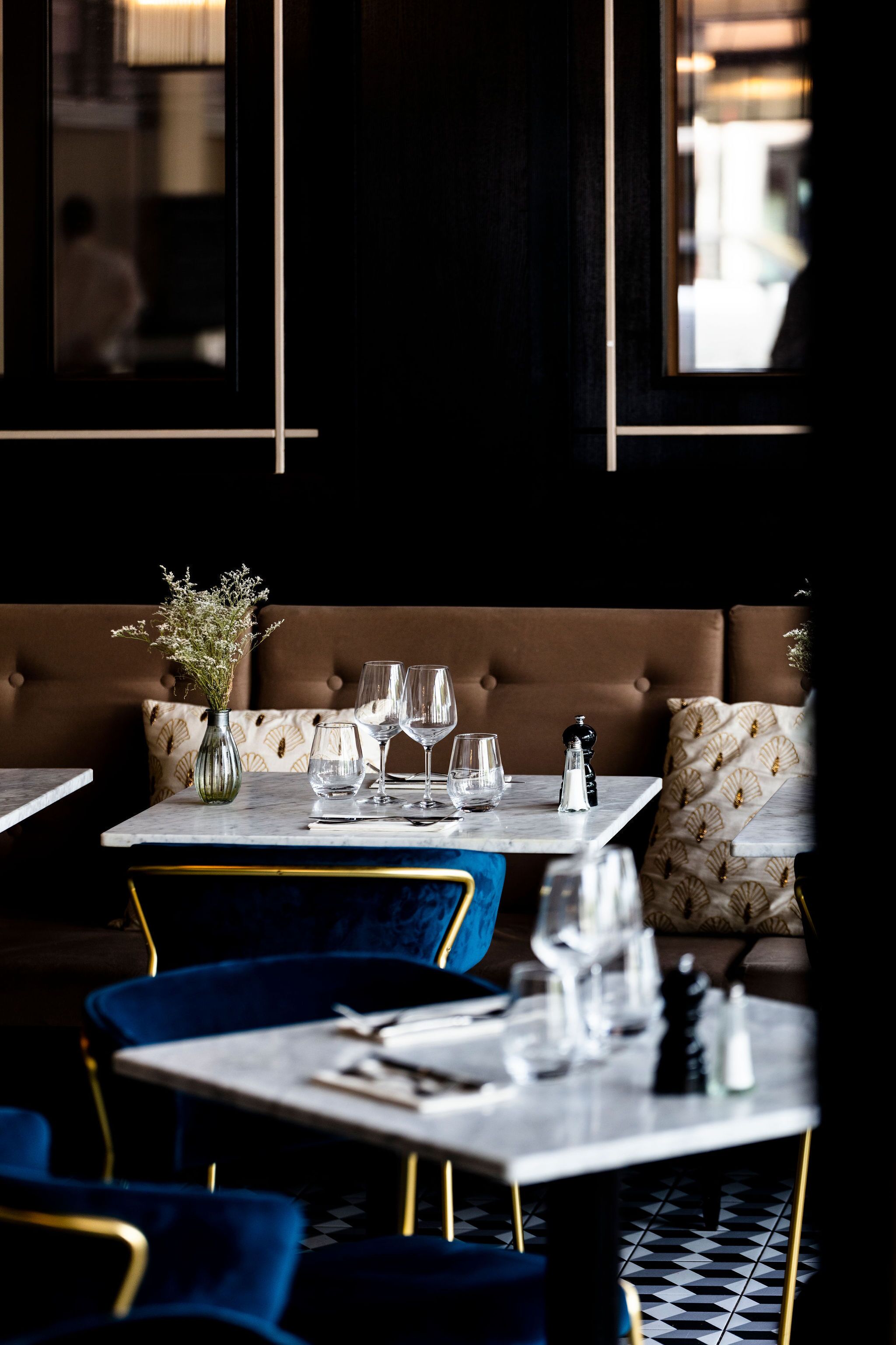Ein Restaurantinneres mit einer Sitzecke, Tischen mit Stühlen und einem Blumenstrauß auf dem Tisch.