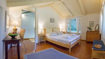 A bedroom with a wooden bed, bedside tables, a chair, and a desk with a bowl of fruit.