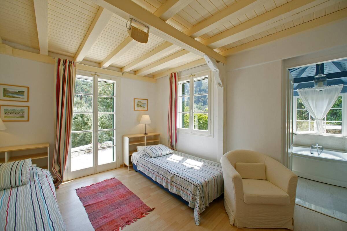 A room with a bed, a chair, a small table, and a window with curtains.