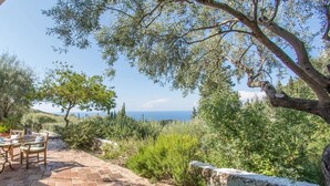 Um pátio com mesa e cadeiras, oferecendo uma vista panorâmica do mar.