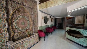 Un hall con un papel tapiz estampado, zona de estar y mostrador de recepción.