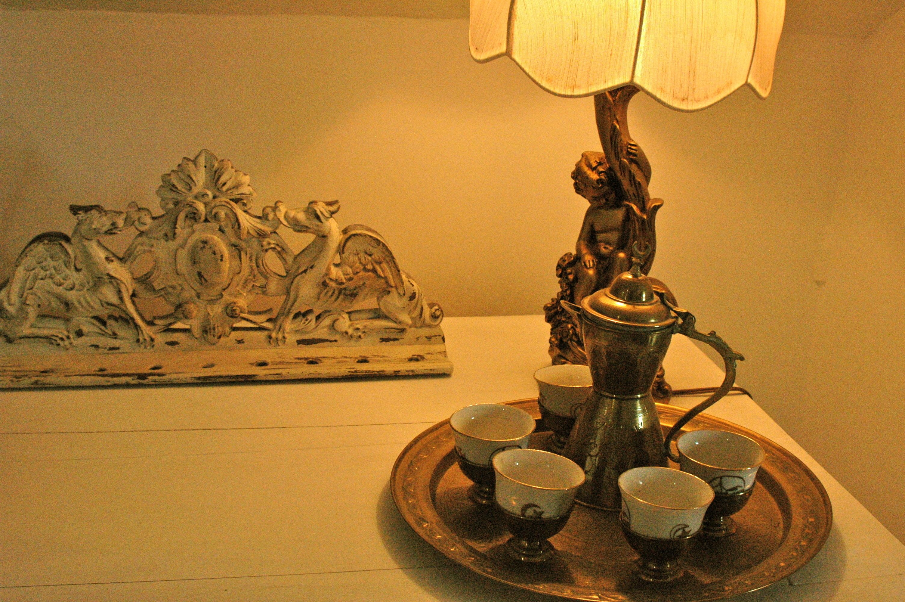 Una bandeja con cuatro tazas y una tetera sobre una mesa, acompañada por una escultura decorativa.
