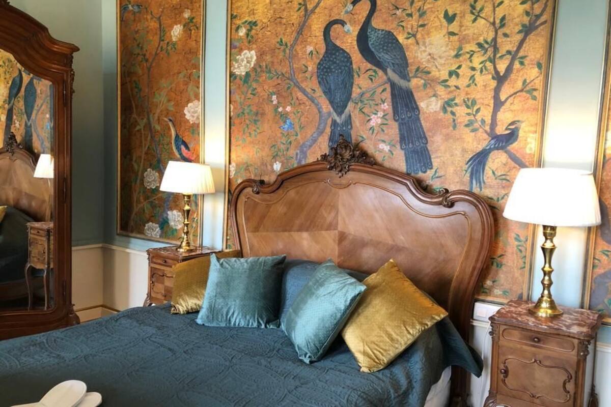 Une chambre avec un grand lit, deux tables de chevet et une fresque murale.