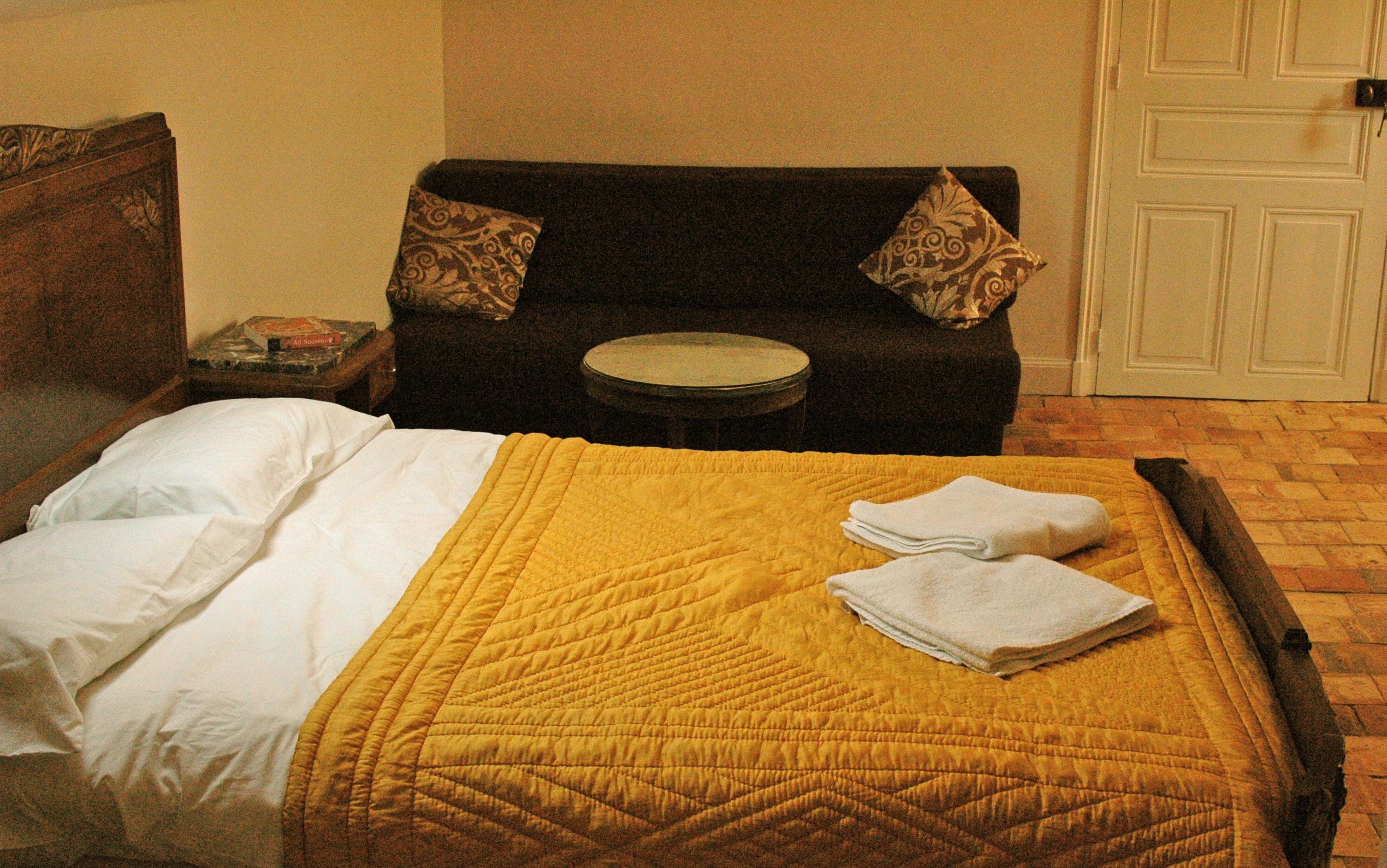 Una habitación de hotel con una cama, un sofá, una mesita redonda y una puerta.