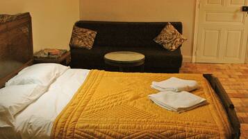 Una habitación de hotel con una cama, un sofá, una mesita redonda y una puerta.