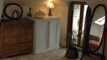 A room with a wooden dresser, a white cabinet, a lamp, a mirror, and a potted plant.