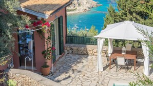 Une terrasse avec une table et des chaises, un parasol blanc et une vue sur la mer.
