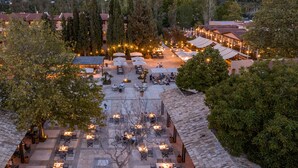 Un espace de restauration en plein air, doté de plusieurs tables et chaises, et entouré d’arbres et d’immeubles.