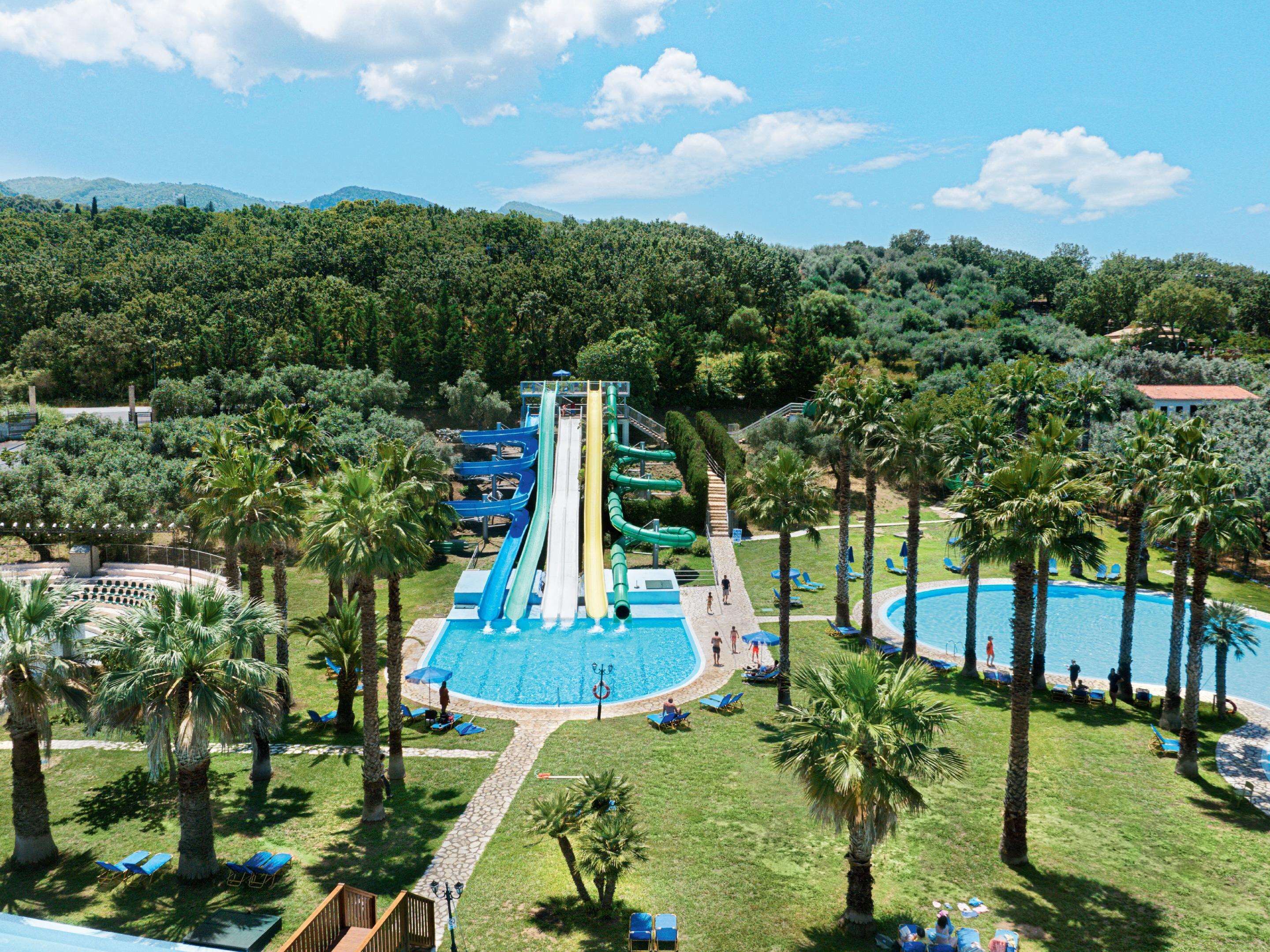 Parque acuático con varias toboganes, una piscina y palmeras.