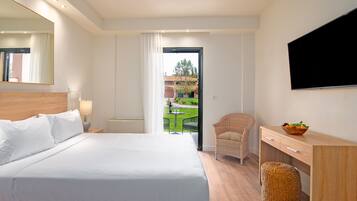 Habitación de hotel con cama, escritorio, silla, televisor y vista al exterior.