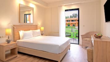 Habitación de hotel con una cama grande, mesitas de noche, un espejo, un televisor y vistas al jardín exterior a través de la puerta.
