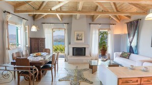 Un cuarto acogedor con comedor, chimenea, sofá y vistas al exterior.
