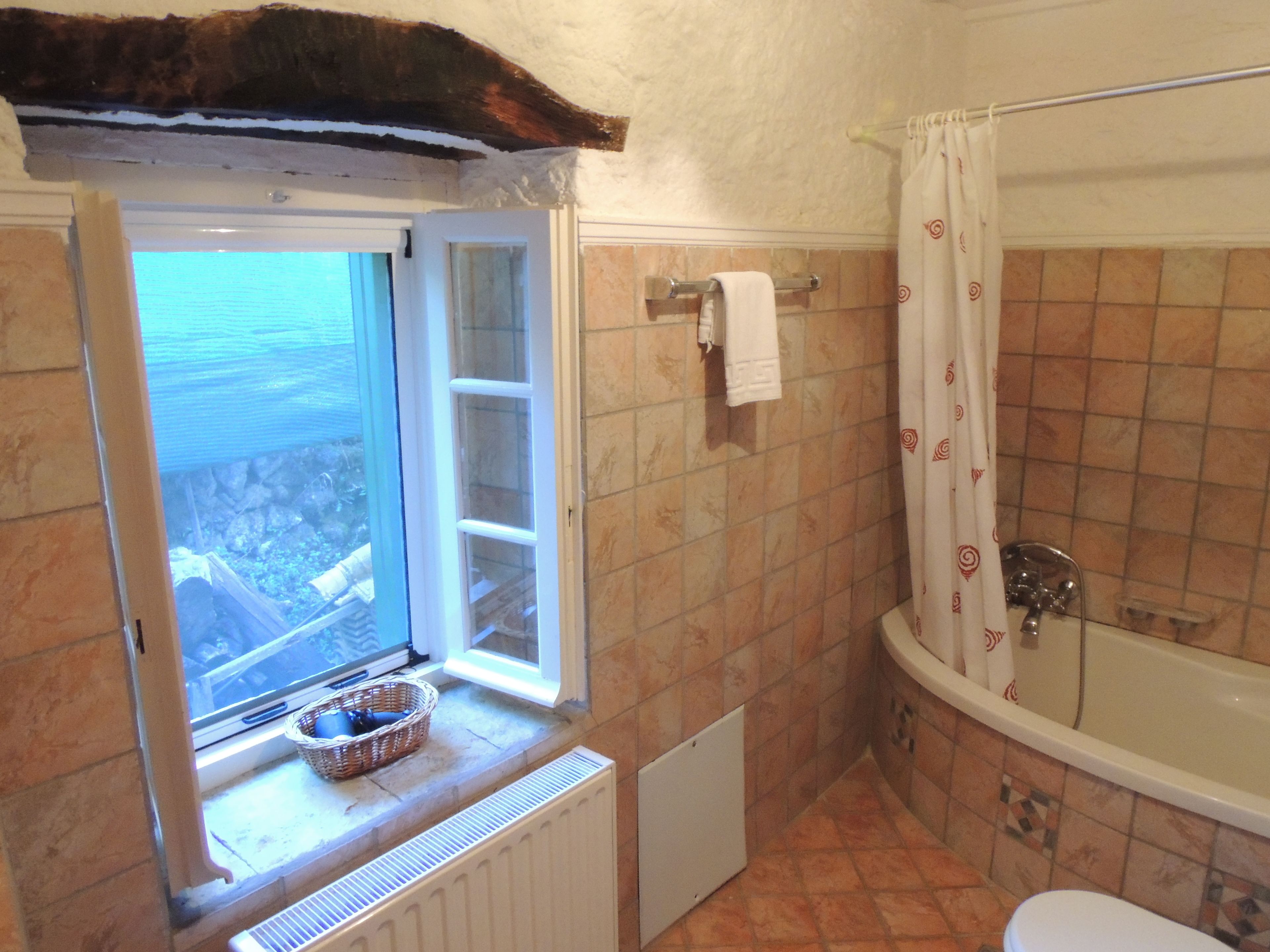 A bathroom with a bathtub, a window with a view, and a radiator.