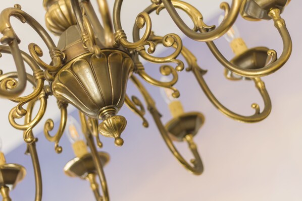 A close-up of a chandelier with intricate metalwork and multiple light fixtures. - Borbò de Charme (Naples)