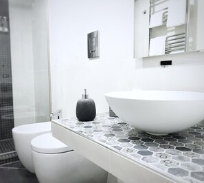 A modern bathroom with a white sink, a black soap dispenser, and a white toilet. - Borbò de Charme (Naples)